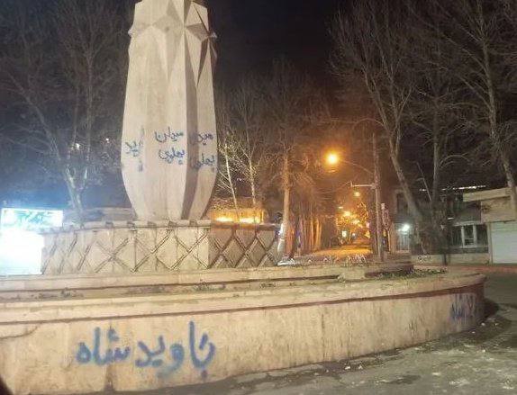 Monument marked with Persian protest graffiti at night
